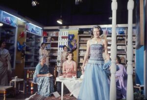 A model showcases a handcrafted, eco-friendly blue gown at the Tel Aviv Lifestyle Expo, where sustainable fashion takes center stage. Attendees, including designers and dignitaries, observe the runway show in a boutique-style setting filled with artisanal products—highlighting Israel’s growing commitment to ethical and environmentally conscious fashion in 2025.